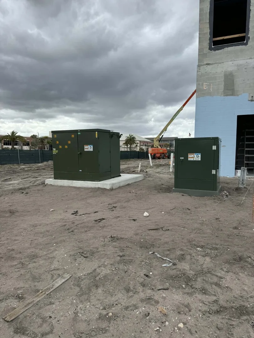 John Deere excavator lifting an underground utility cabinet