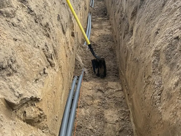 Deep trench with conduit and excavator tracks